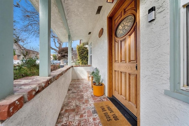 entrance to property featuring covered porch and stucco siding