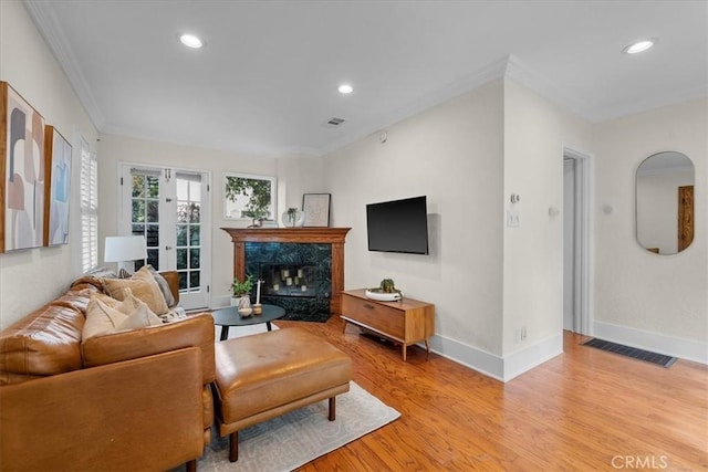 living room featuring baseboards, visible vents, light wood finished floors, recessed lighting, and ornamental molding