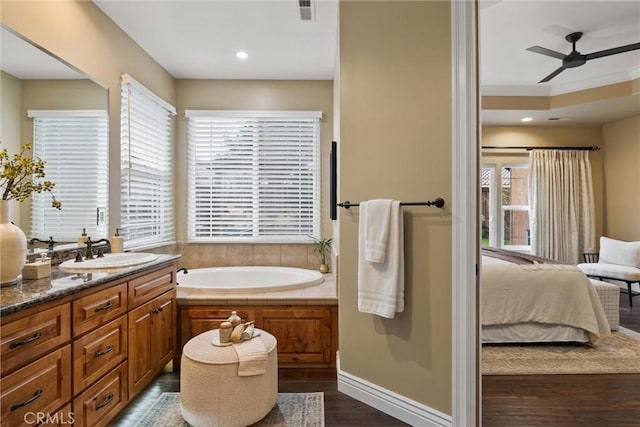 ensuite bathroom featuring ensuite bathroom, wood finished floors, a bath, ceiling fan, and vanity