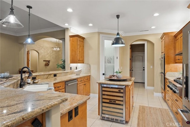 kitchen featuring a sink, a center island, wine cooler, arched walkways, and appliances with stainless steel finishes