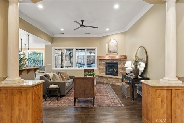 living area featuring a stone fireplace, dark wood-style floors, a ceiling fan, and ornate columns