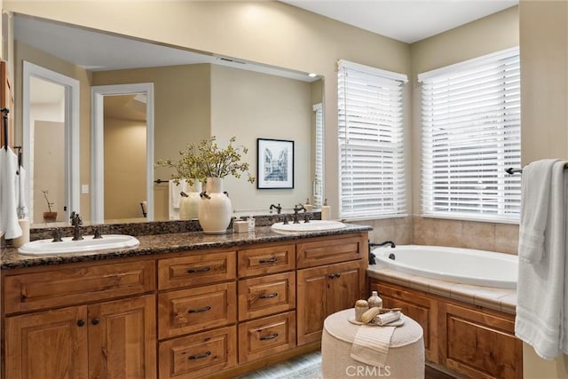 bathroom with double vanity, a bath, and a sink