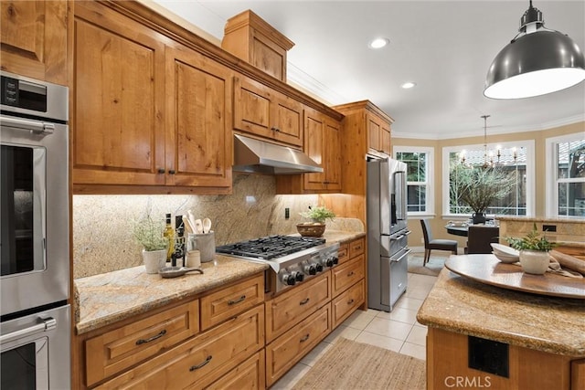 kitchen featuring under cabinet range hood, appliances with stainless steel finishes, brown cabinetry, and crown molding