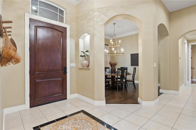 foyer featuring light tile patterned floors, baseboards, arched walkways, and a chandelier