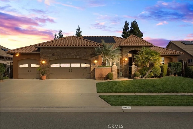 mediterranean / spanish-style house with driveway, stone siding, a garage, solar panels, and a tiled roof