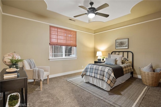 bedroom with visible vents, baseboards, a tray ceiling, carpet flooring, and a ceiling fan