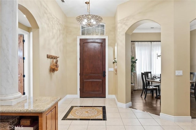 entryway featuring an inviting chandelier, light tile patterned floors, baseboards, and arched walkways