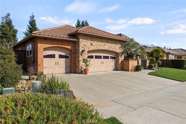 mediterranean / spanish house with stucco siding, stone siding, fence, a garage, and a tiled roof