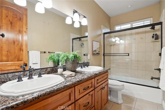 bathroom with tile patterned flooring, double vanity, bath / shower combo with glass door, and a sink