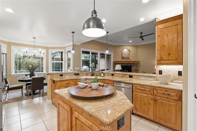 kitchen featuring a kitchen island, crown molding, dishwasher, a stone fireplace, and light tile patterned flooring