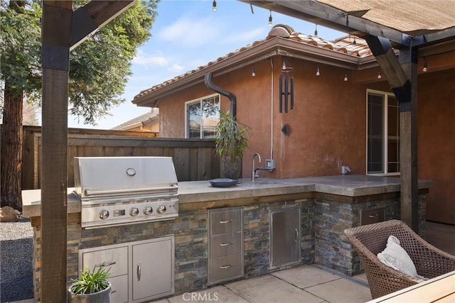 view of patio / terrace featuring a sink, a grill, an outdoor kitchen, and fence