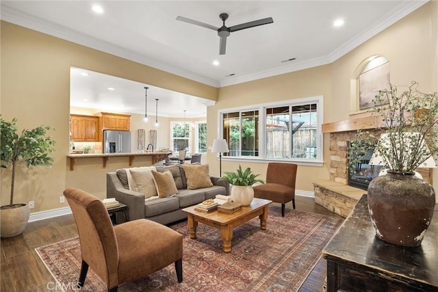 living area with dark wood-style floors, a fireplace, crown molding, and baseboards