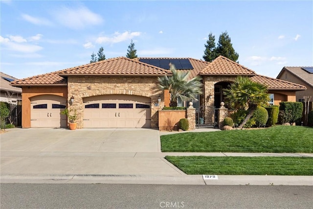 mediterranean / spanish home featuring stucco siding, driveway, a front lawn, stone siding, and an attached garage