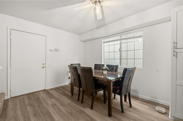 dining space with light wood-style flooring, a ceiling fan, and baseboards