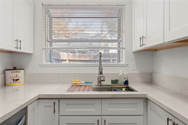 kitchen with white cabinetry, light countertops, and a sink