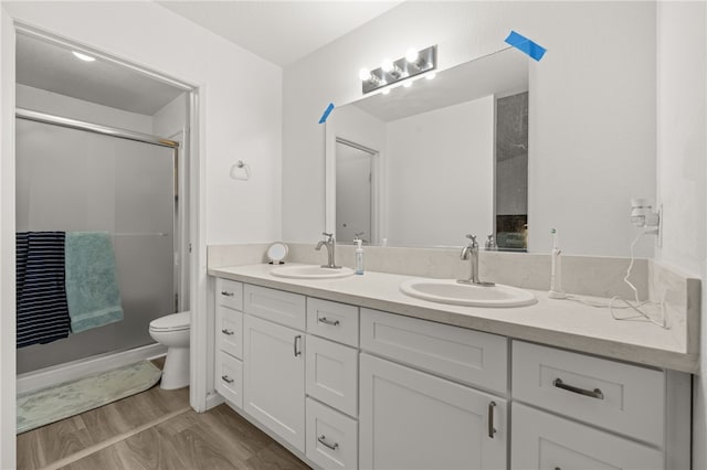 bathroom with double vanity, toilet, wood finished floors, and a sink