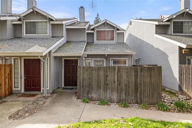 view of property featuring a shingled roof and fence