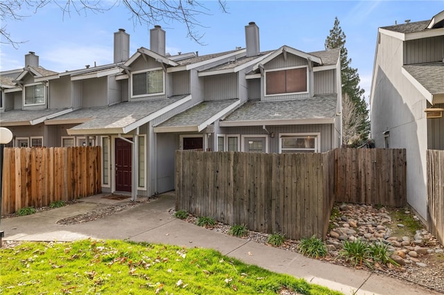 view of property with fence private yard and roof with shingles