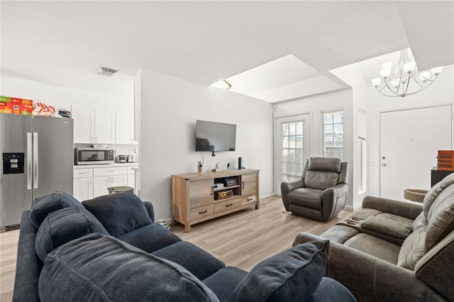 living room featuring visible vents, an inviting chandelier, and light wood finished floors