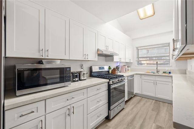 kitchen with light wood-style flooring, a sink, stainless steel appliances, white cabinets, and under cabinet range hood