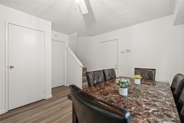 dining space with stairs, a ceiling fan, and light wood-type flooring