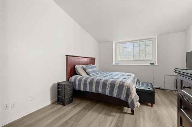 bedroom featuring light wood finished floors, baseboards, and vaulted ceiling