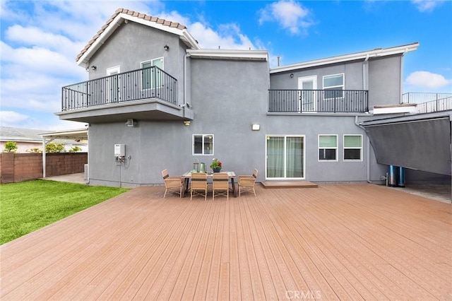 back of house with stucco siding, outdoor dining area, a balcony, and fence