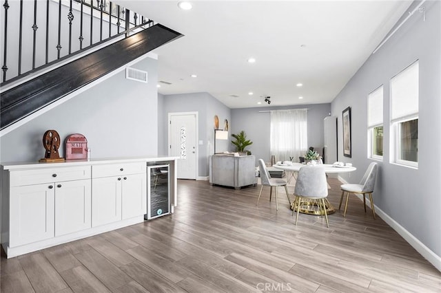 interior space with visible vents, wine cooler, stairs, light wood-type flooring, and recessed lighting