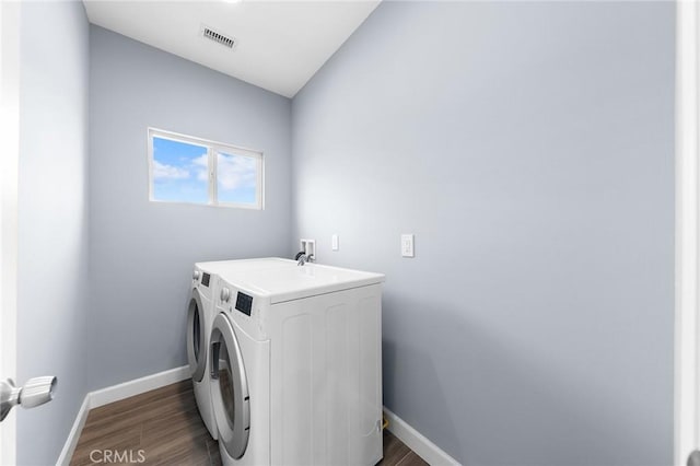 clothes washing area with laundry area, baseboards, dark wood-style flooring, and washing machine and clothes dryer