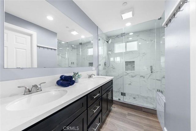 full bathroom with a marble finish shower, recessed lighting, double vanity, and a sink