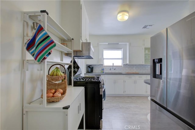 kitchen featuring tasteful backsplash, visible vents, white cabinets, stainless steel appliances, and a sink