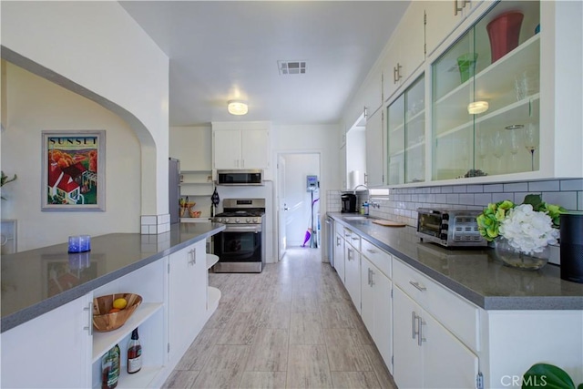 kitchen featuring visible vents, open shelves, a sink, appliances with stainless steel finishes, and backsplash