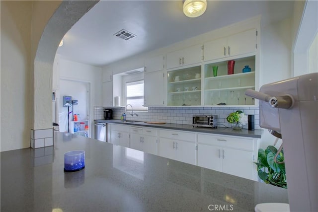 kitchen featuring open shelves, arched walkways, a sink, white cabinets, and backsplash