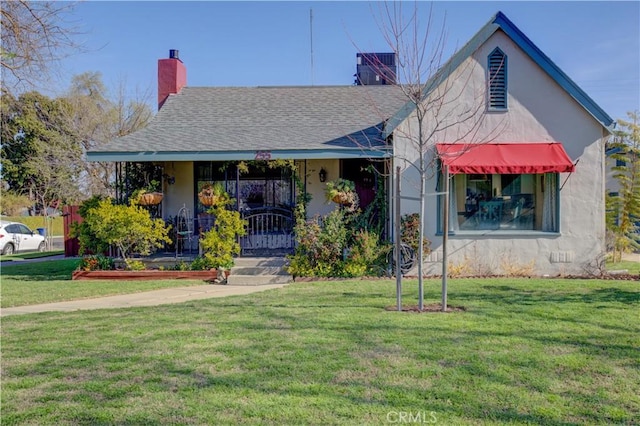 view of front of home featuring stucco siding, a porch, a chimney, and a front yard