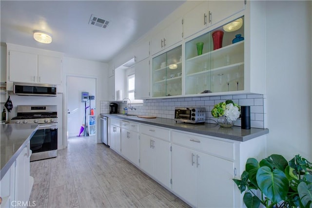 kitchen featuring tasteful backsplash, visible vents, a toaster, stainless steel appliances, and a sink