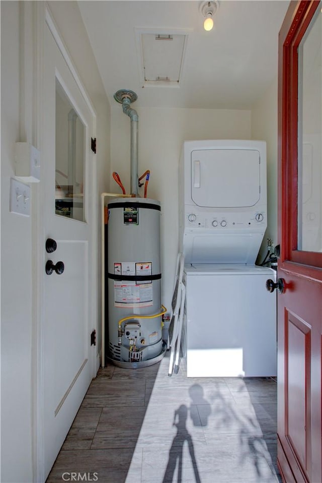 clothes washing area with laundry area, gas water heater, wood finished floors, and stacked washer and clothes dryer