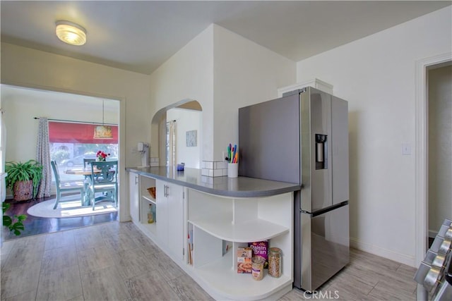 kitchen with baseboards, open shelves, stainless steel fridge with ice dispenser, arched walkways, and light wood-type flooring