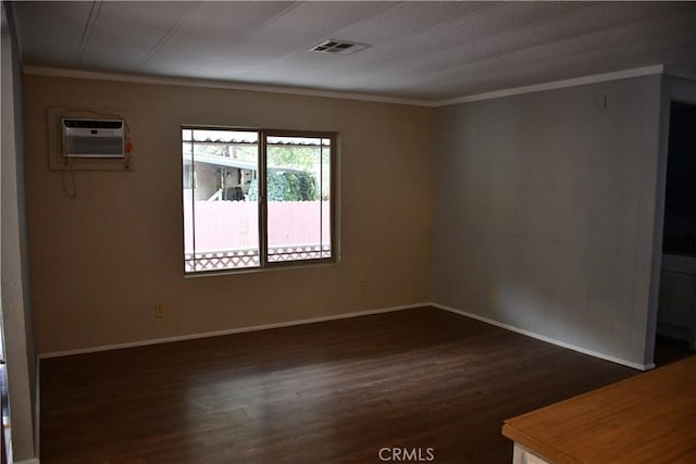 unfurnished room featuring a wall mounted air conditioner, visible vents, dark wood-style floors, and crown molding