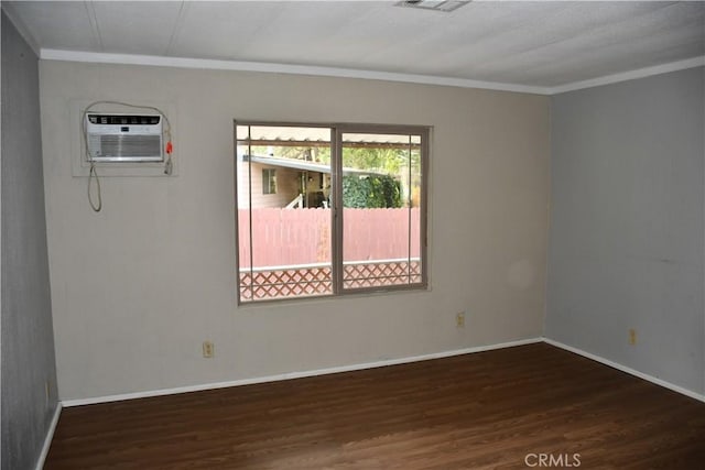 spare room featuring visible vents, baseboards, ornamental molding, wood finished floors, and a wall mounted AC