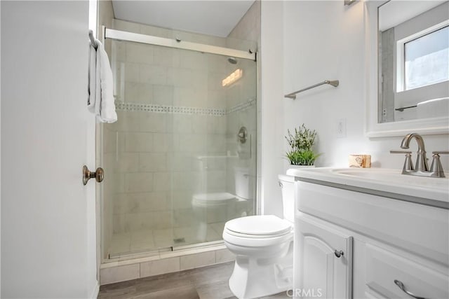 bathroom with vanity, toilet, wood finished floors, and a shower stall