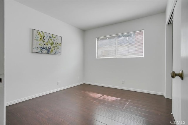 unfurnished bedroom with baseboards and dark wood-style floors