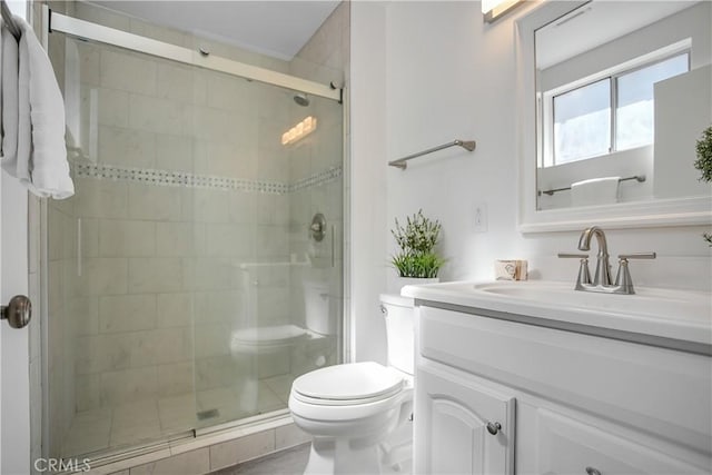 full bathroom with a stall shower, toilet, and vanity