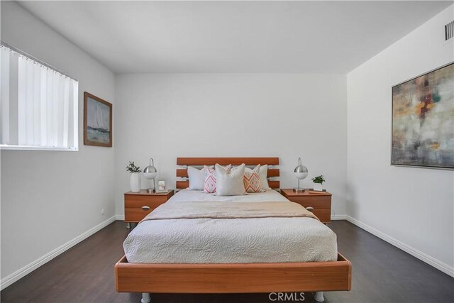 bedroom with visible vents, baseboards, and wood finished floors