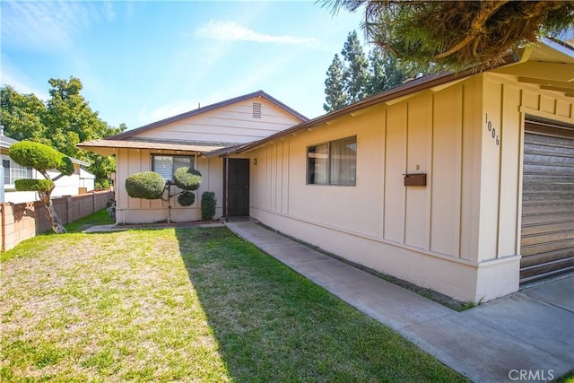 view of front of property with board and batten siding, a front yard, and fence