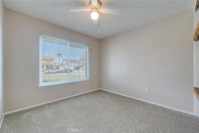 spare room featuring a ceiling fan, baseboards, a textured ceiling, and carpet flooring