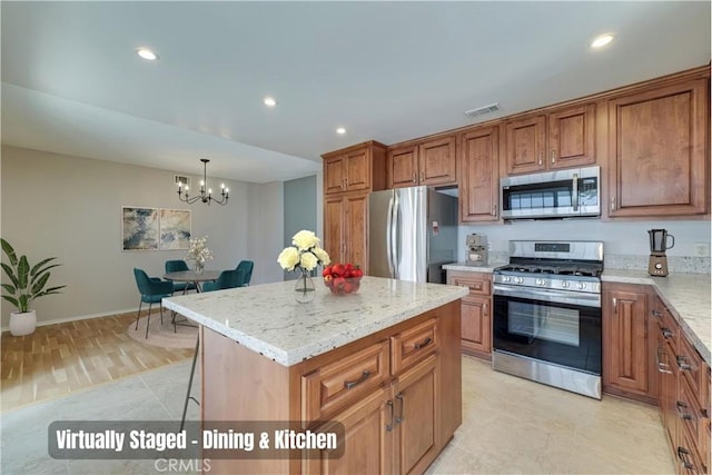 kitchen with light stone counters, brown cabinetry, visible vents, appliances with stainless steel finishes, and a center island