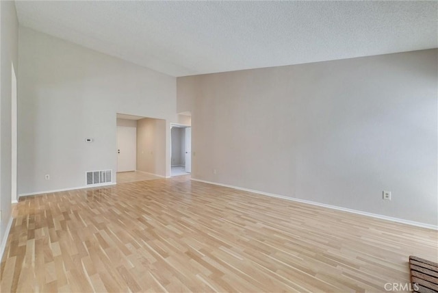 unfurnished room featuring visible vents, baseboards, high vaulted ceiling, light wood-style flooring, and a textured ceiling