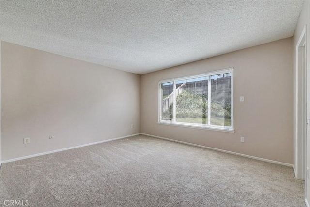 unfurnished room with carpet, baseboards, and a textured ceiling