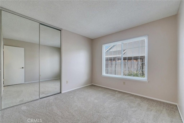 unfurnished bedroom featuring a closet, baseboards, a textured ceiling, and carpet