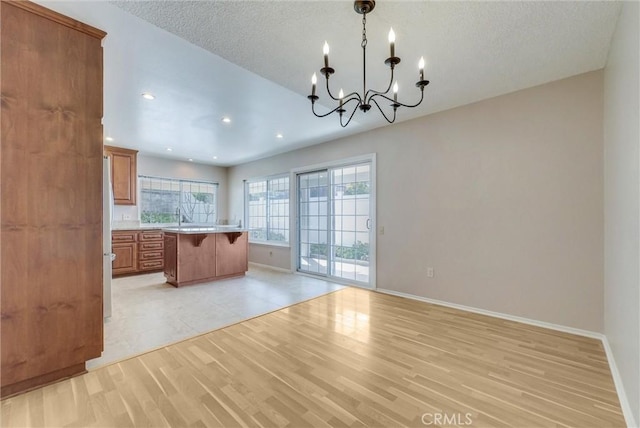 kitchen featuring light wood finished floors, a breakfast bar, light countertops, brown cabinets, and a chandelier